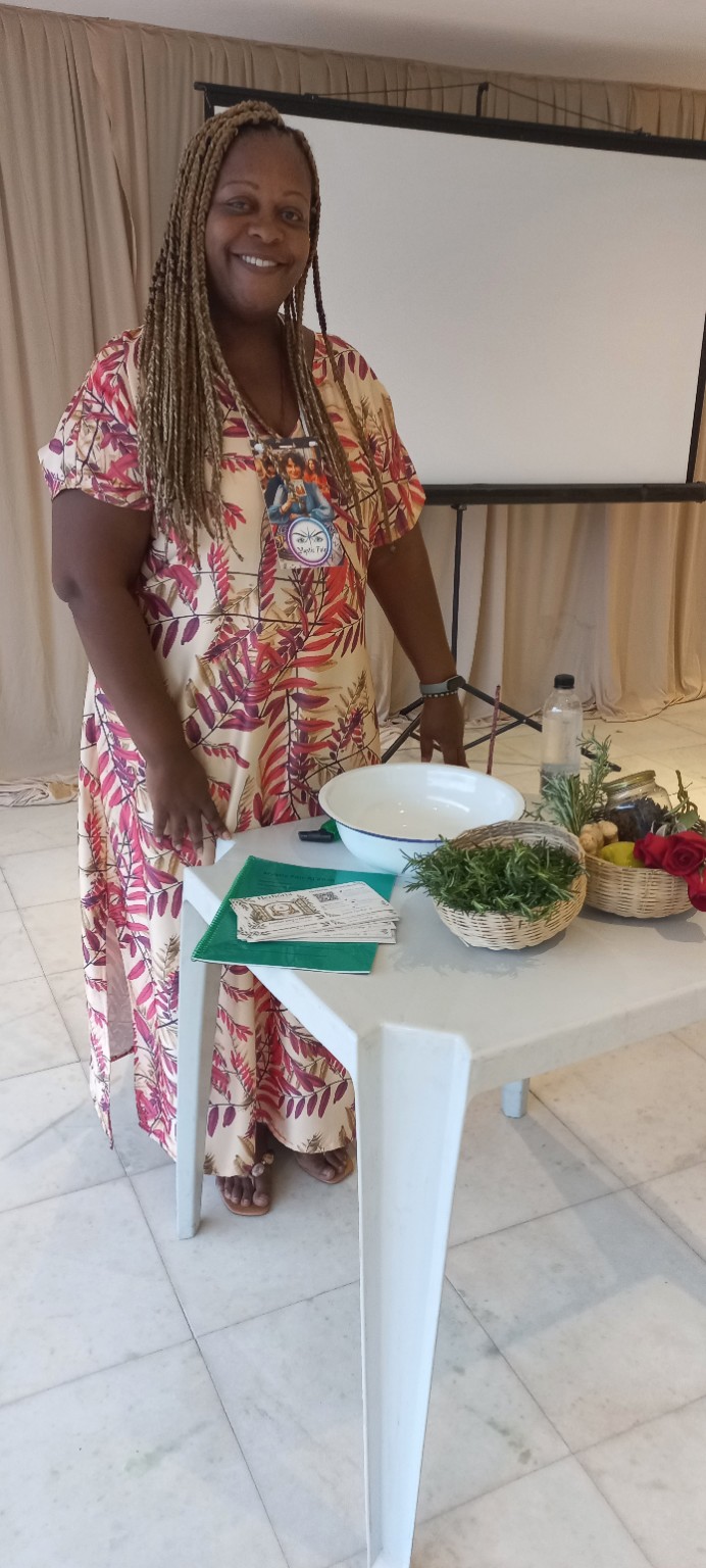 Luciane Osundaye junto à mesa de plantas e materiais da Herbória
